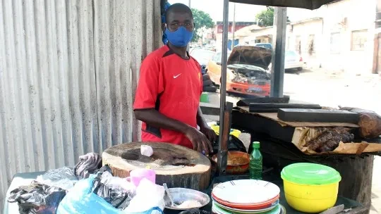 A mask-wearing man sells 'choukouya', seasoned and braised mutton and beef in Treichville, a working-class district of Abidjan, the economic capital of Côte d'Ivoire. Informal workers have been among those most affected economally by COVID-19 (Photo: Jennifer A. Patterson/ILO via Flickr, CC BY-NC-ND 2.0)